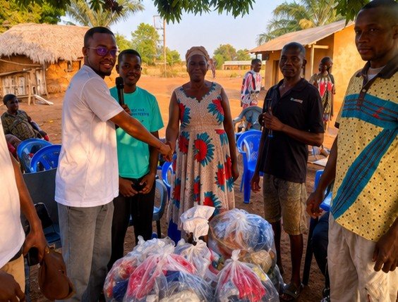 Dzidzeme Foundation volunteer presenting a gift to a community elder at Debidebi, Kpando