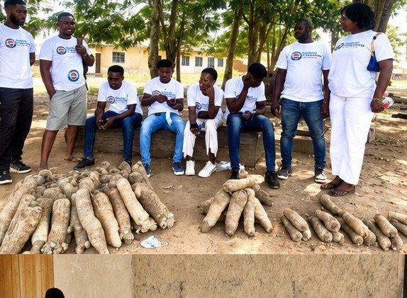 Volunteers seated with a family and their yam harvest